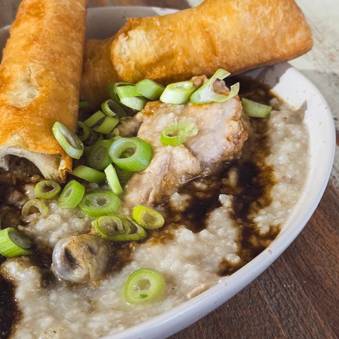 Bowl of congee with chicken on a wooden table