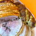 Sliced roasted pork with crispy skin on a white plate against an orange background