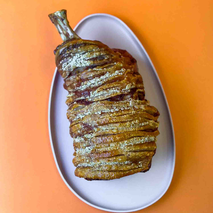 Crackling pork roast on a white plate with an orange background
