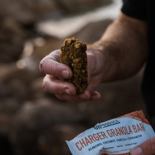 Person holding a granola bar with a blurred natural background